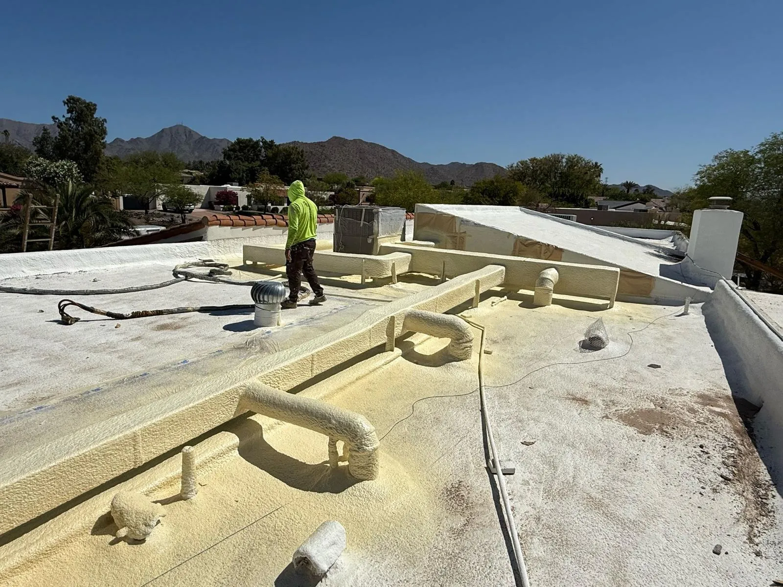 Roofer applying spray foam roofing on a flat roof in Arizona